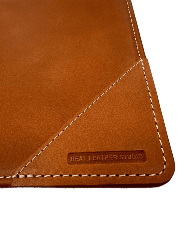 Detalle macro del sello de calidad Real Leather Studio grabado a fuego en la piel del vade.