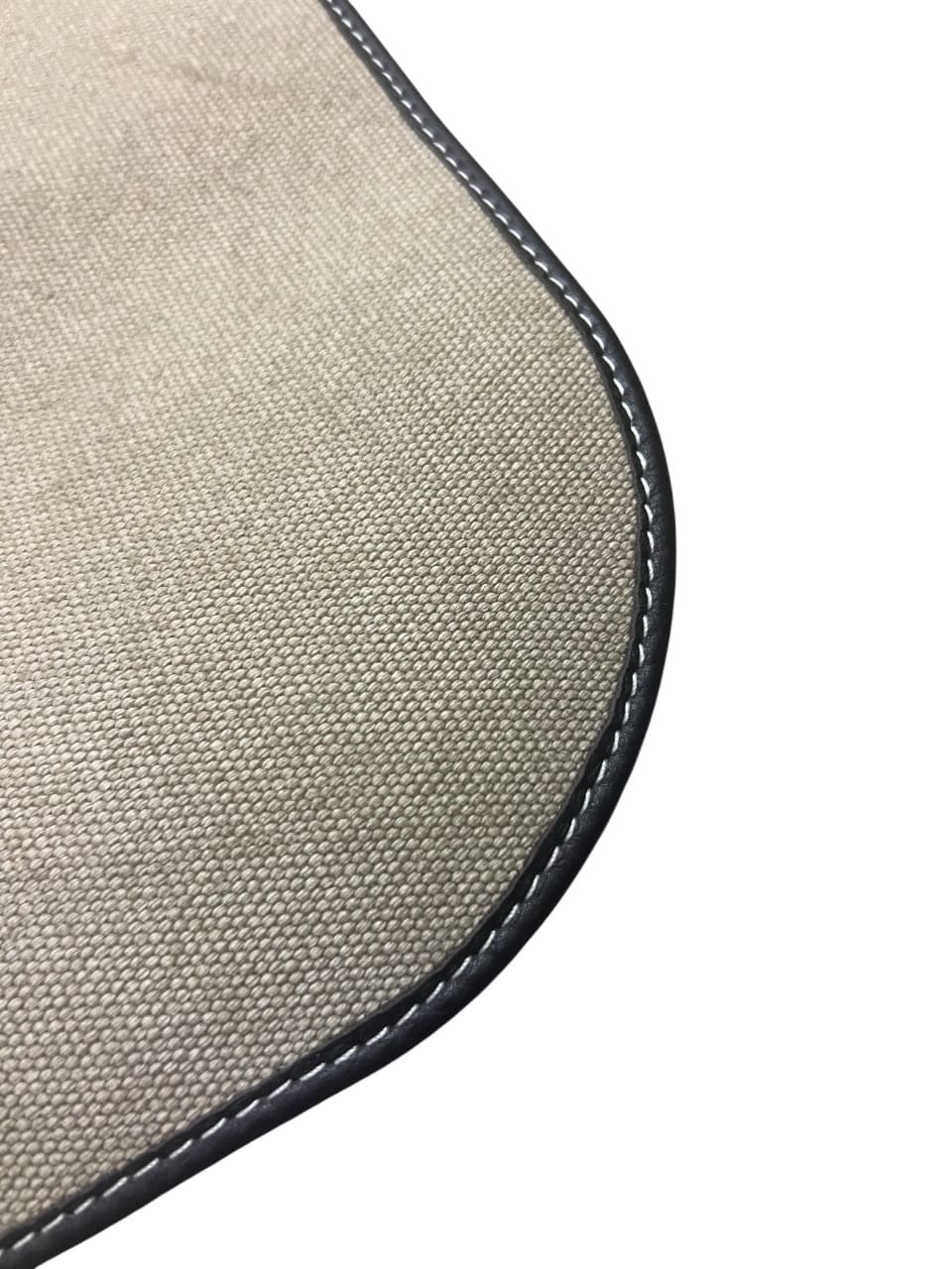 Close-up of the durable canvas fabric texture and dark leather piping detail.